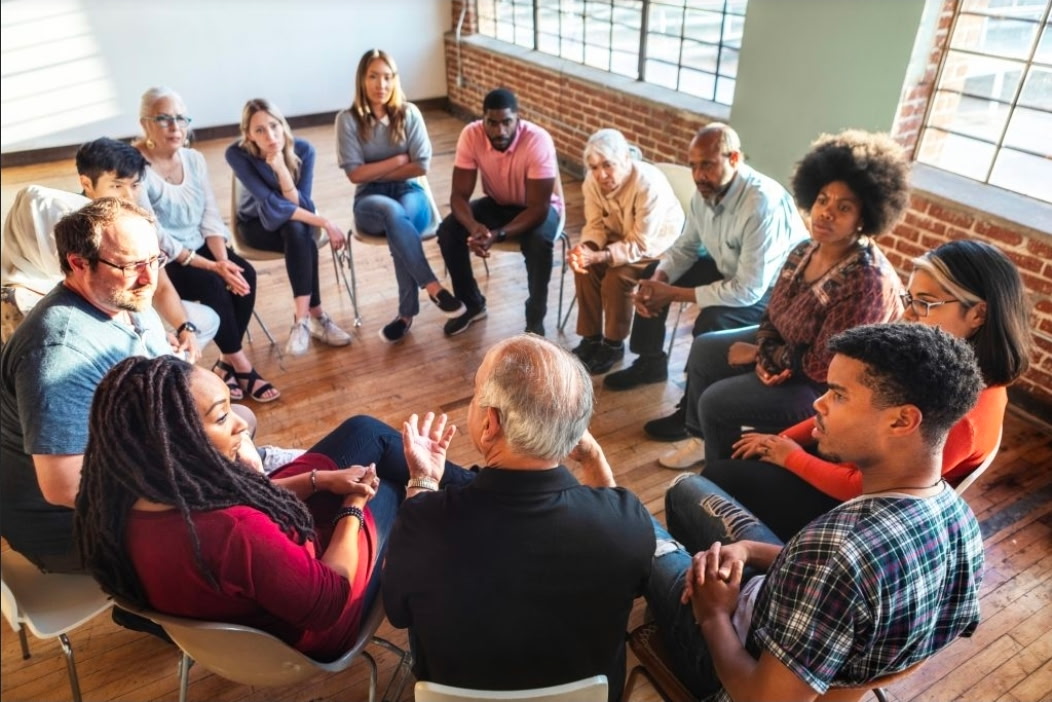 Illustrative photo of a diverse group of adults seated in a circle